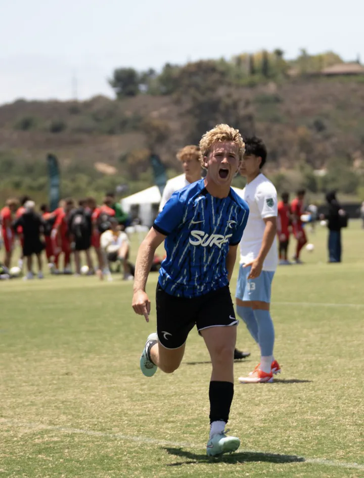 Soccer player in a blue jersey runs forward in celebration.